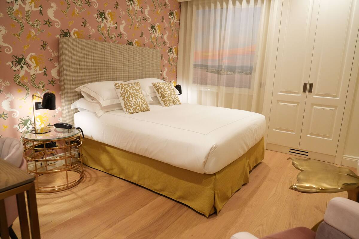Ein ordentlich eingerichtetes Schlafzimmer mit einem großen Bett, einem Nachttisch mit Lampe und einem Kleiderschrank.