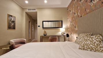 Habitación de hotel con una cama grande, un escritorio, una silla y un espejo decorativo.