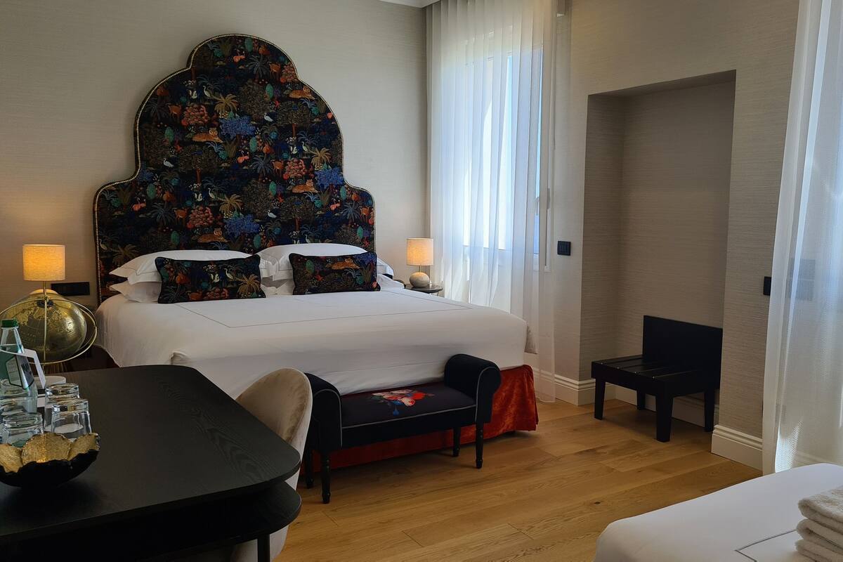 Ein Hotelzimmer mit einem großen Bett, einem Schreibtisch, einem Stuhl und einem kleinen Tisch.