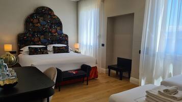 Una camera d'albergo con un letto grande, una scrivania, una sedia e un tavolino.