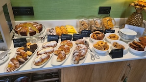 A variety of pastries and desserts displayed on a counter with labels indicating different types. - Jolly Charme Suite (Messina)