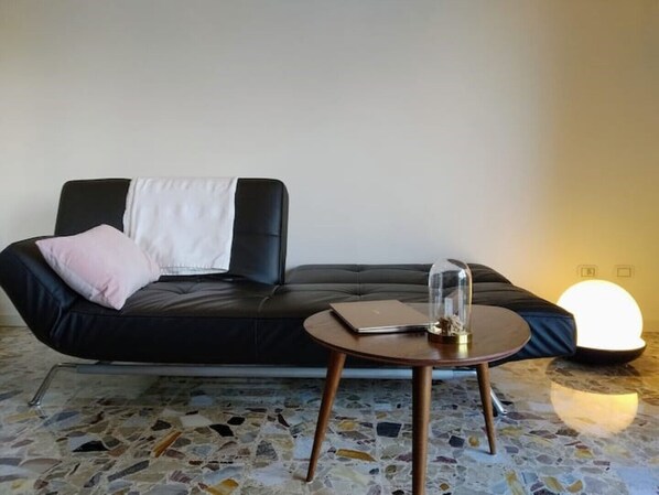 A modern living room with a black leather sofa, a round wooden coffee table, and a mosaic tile floor. - Renovated, amazing lake view (Perledo)
