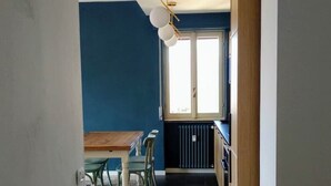 A narrow hallway with a dining area at the end, featuring a table and chairs, a radiator, and a window with a view. - Renovated, amazing lake view (Perledo)