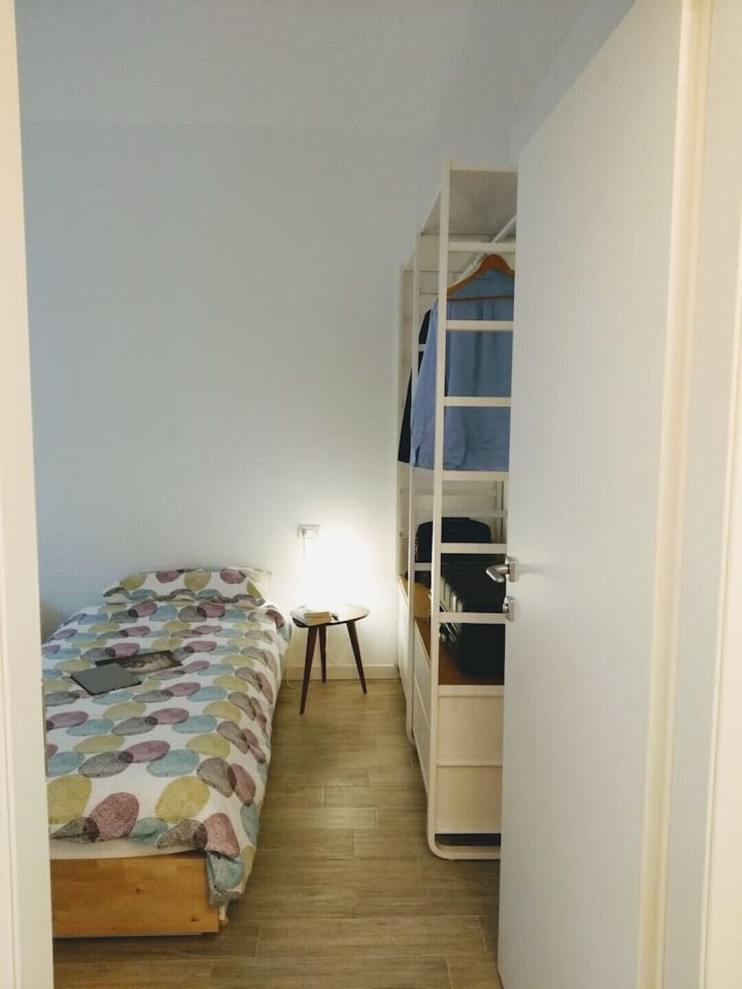 A small, narrow room with a bed, a small table, and a built-in wardrobe.