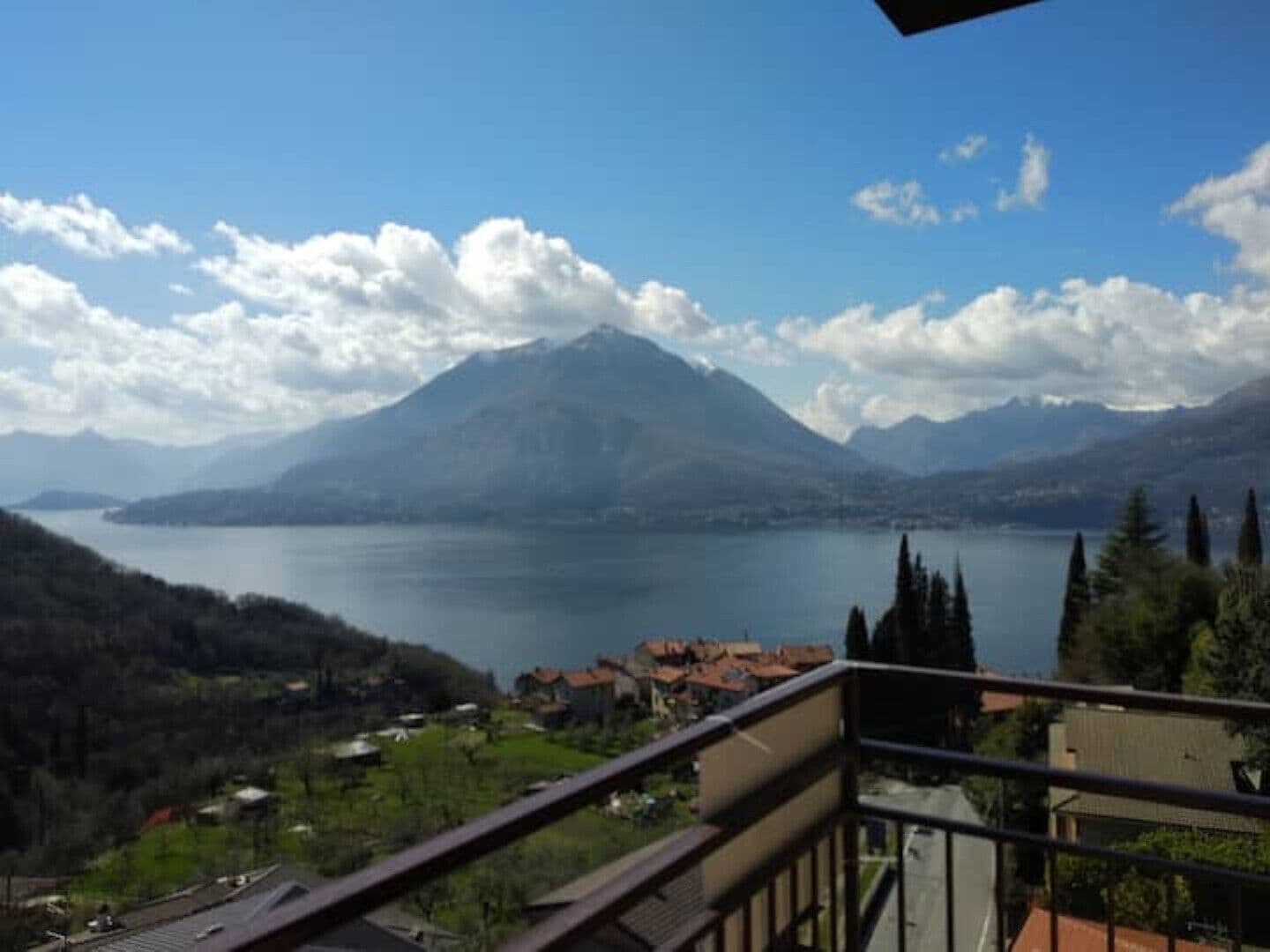 Bergzicht met een meer en een balkon dat uitkijkt over een woonwijk.