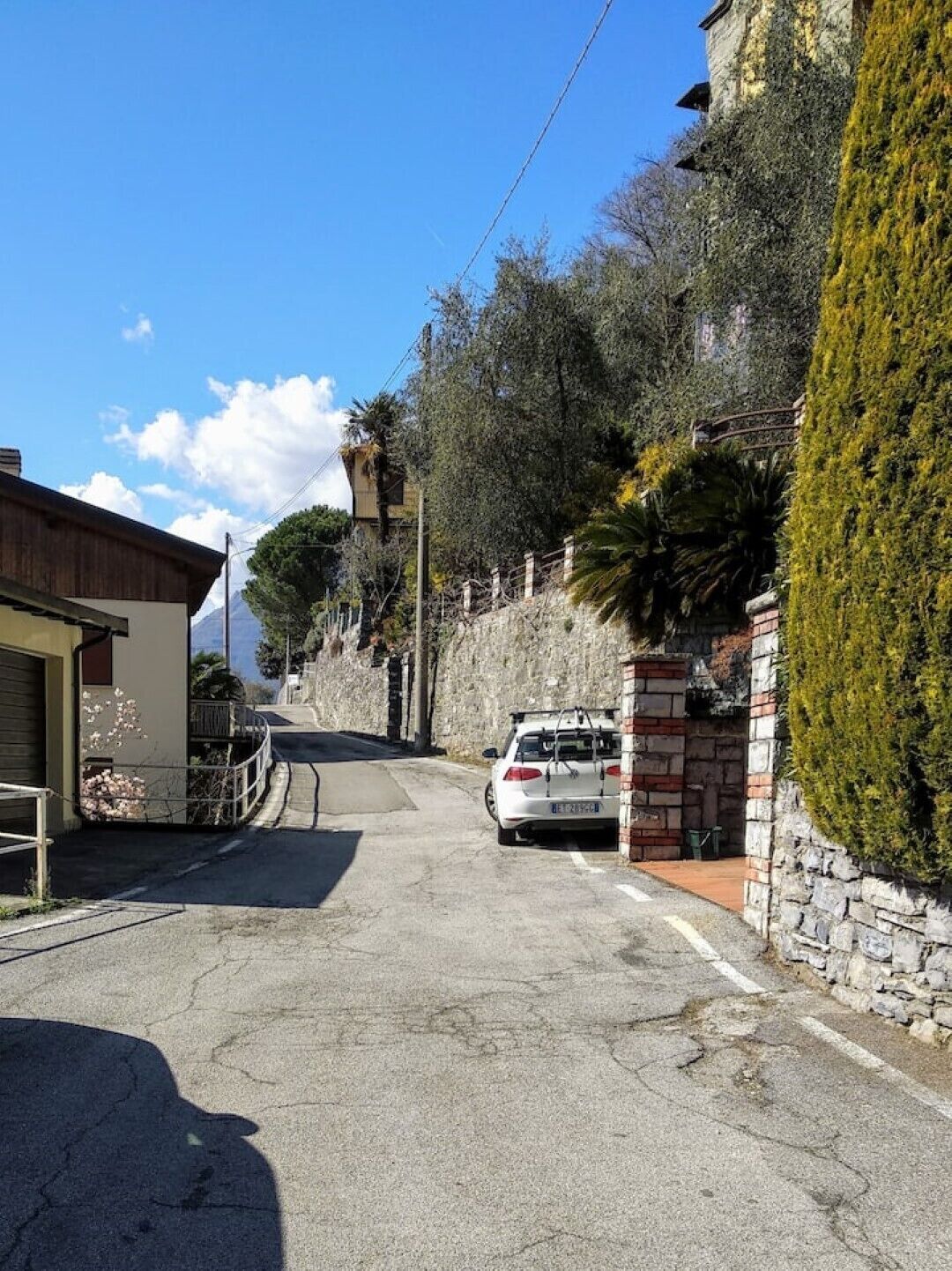 Un vicolo stretto con un'auto parcheggiata, muri in pietra e un edificio con facciata in legno.