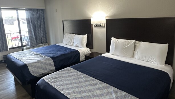 A hotel room with two beds, each with a headboard and bedside lamps. - Oakwood Inn (Oakdale)