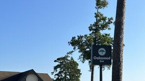 A sign for Oakwood Inn, a building with a white facade and a dark roof, and a parking lot with a few cars. - Oakwood Inn (Oakdale)