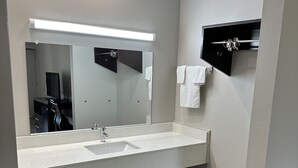 A modern bathroom with a large mirror, a sink, and a towel rack. - Oakwood Inn (Oakdale)