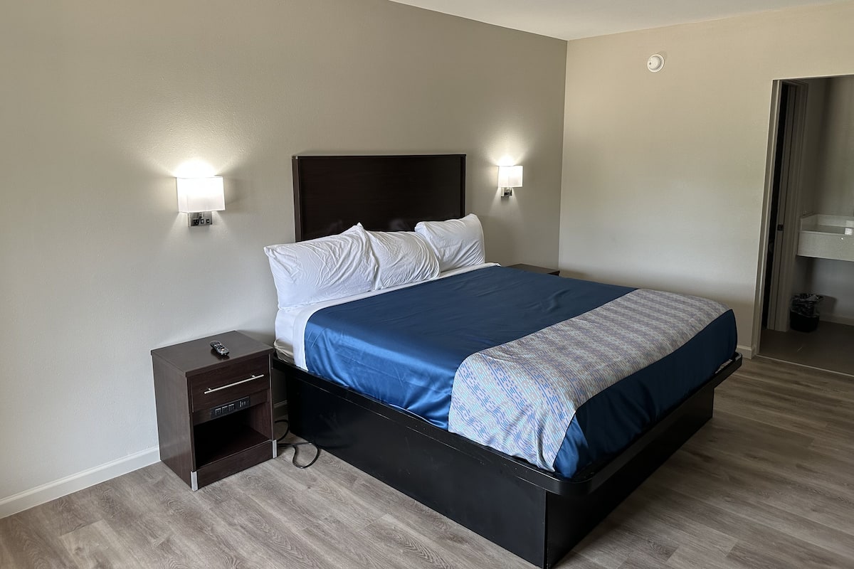 A neatly arranged hotel room with a bed, bedside tables, and wall-mounted lamps.