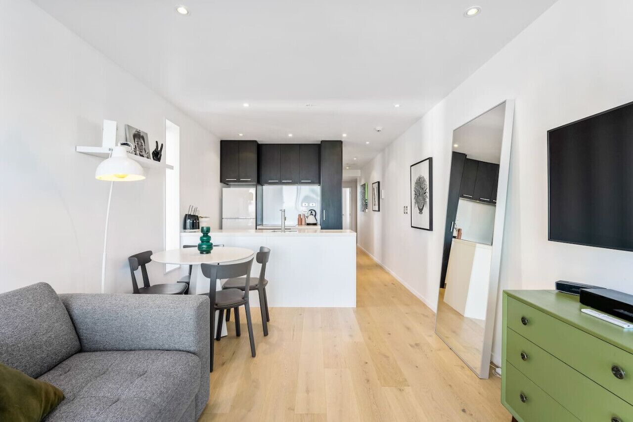A modern apartment with a dining area, kitchenette, and a living space with a sofa and TV.