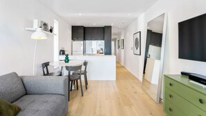 A modern apartment with a dining area, kitchenette, and a living space with a sofa and TV.