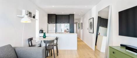 A modern apartment with a dining area, kitchenette, and a living space with a sofa and TV.