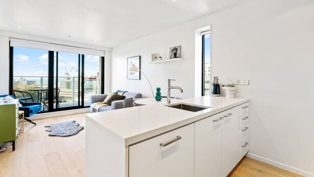 A modern kitchen with a large window, a sink, and a dining area with a view of the city.