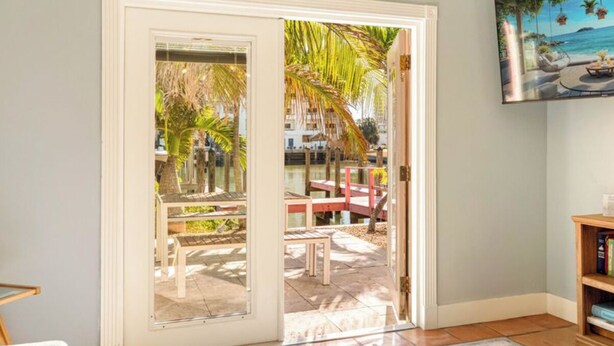 A room with a sliding glass door leading to an outdoor patio with a table and chairs.