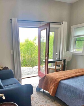 Relax in this stylish room with a large bed, blue armchair, and a table with a lamp.