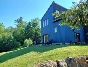Guests can relax in the beautifully landscaped grounds surrounding this two-story building, which features a charming red door and inviting outdoor seating areas.