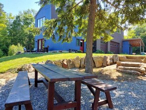 Situated in a lush green space, this home features a garage and a covered outdoor seating area, perfect for relaxation.