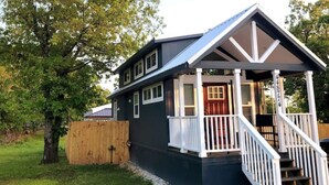 A two-story house with a porch, wooden fence, and a tree in the background. - Tiny Getaway at Ten Killer (Vian)