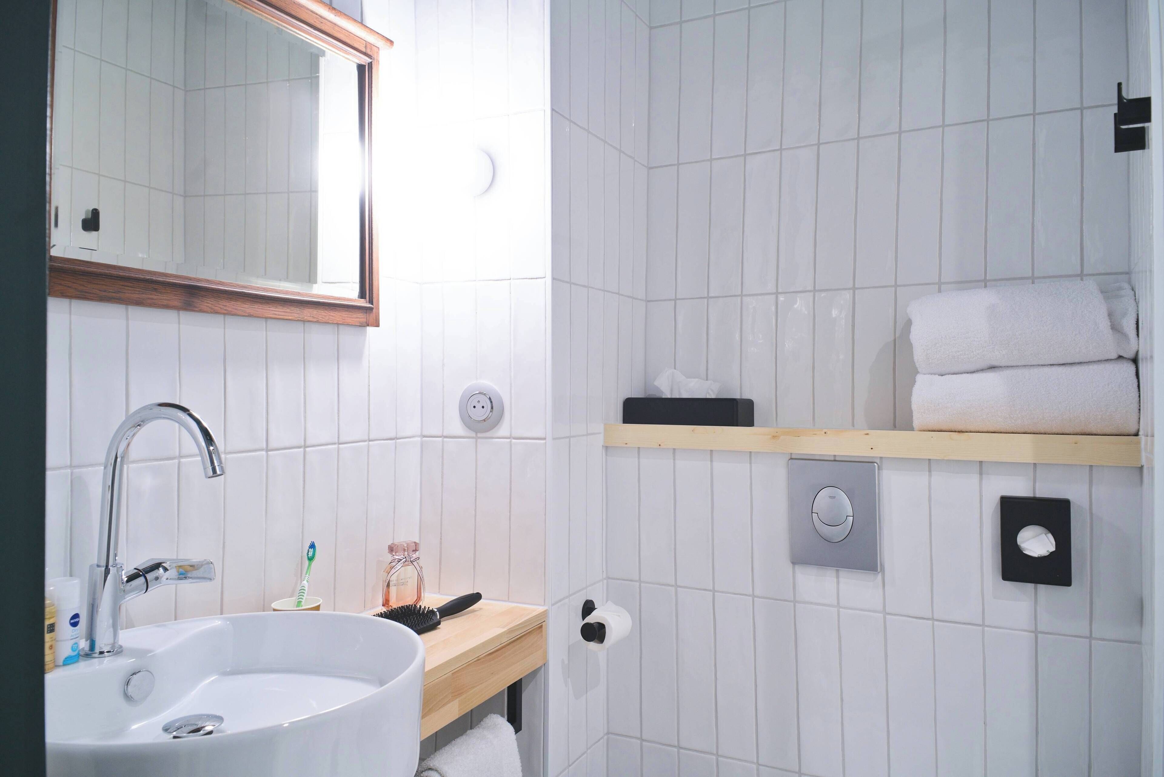 Une salle de bain équipée d’un lavabo, d’un miroir, d’un porte-serviettes et d’une étagère avec des serviettes.