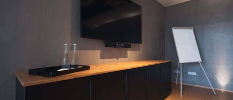 Una sala de conferencias moderna con una gran pantalla plana, una pizarra y un mostrador de madera.
