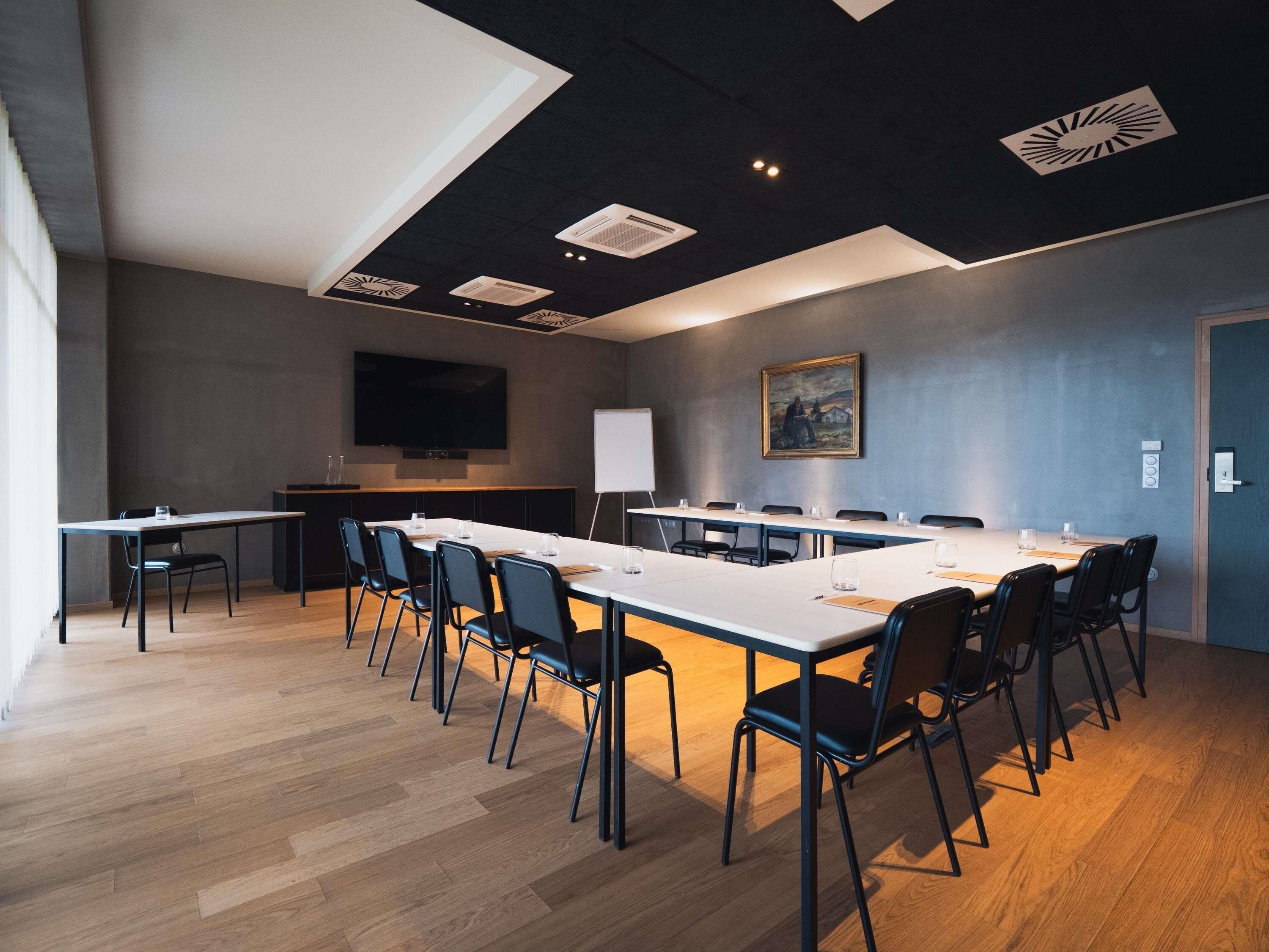 A conference room with a long table, chairs, a whiteboard, and a painting on the wall.