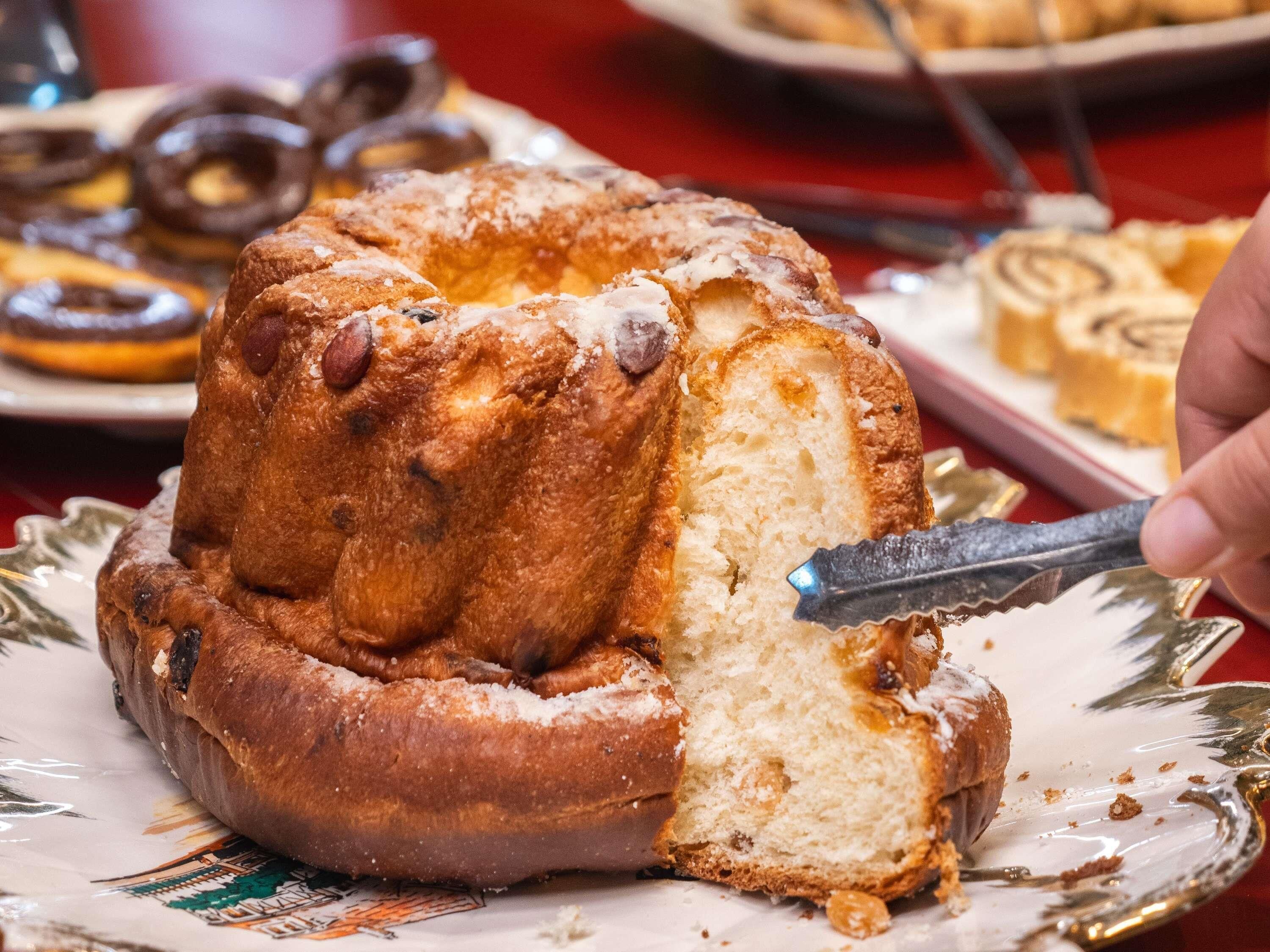 A cake with almonds on top, a knife cutting into it, and a plate with a decorative pattern.