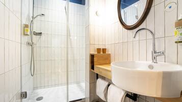 A bathroom with a shower, sink, mirror, and towel rack.