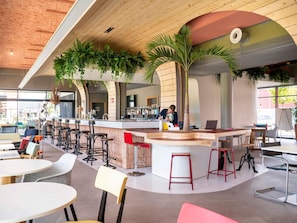 A modern bar area with a curved counter, multiple stools, and a seating area with tables and chairs. - Greet Hotel Cernay Mulhouse (Cernay)
