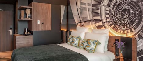 A modern bedroom with a large bed, a wall clock, and a built-in wardrobe.
