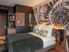 Un dormitorio moderno con una cama grande, un reloj de pared y un armario empotrado.