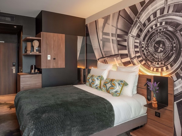 A modern bedroom with a large bed, a wall clock, and a built-in wardrobe.