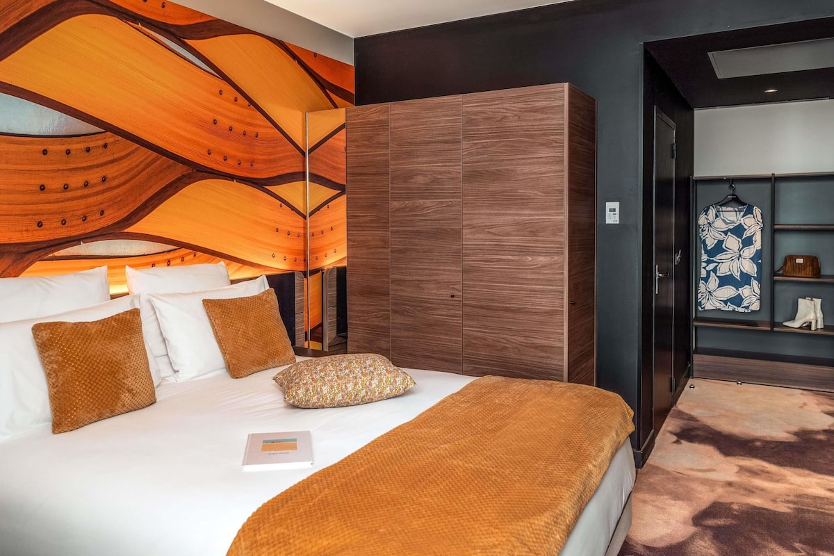A modern hotel room with a large bed, a wardrobe, and a shoe rack.