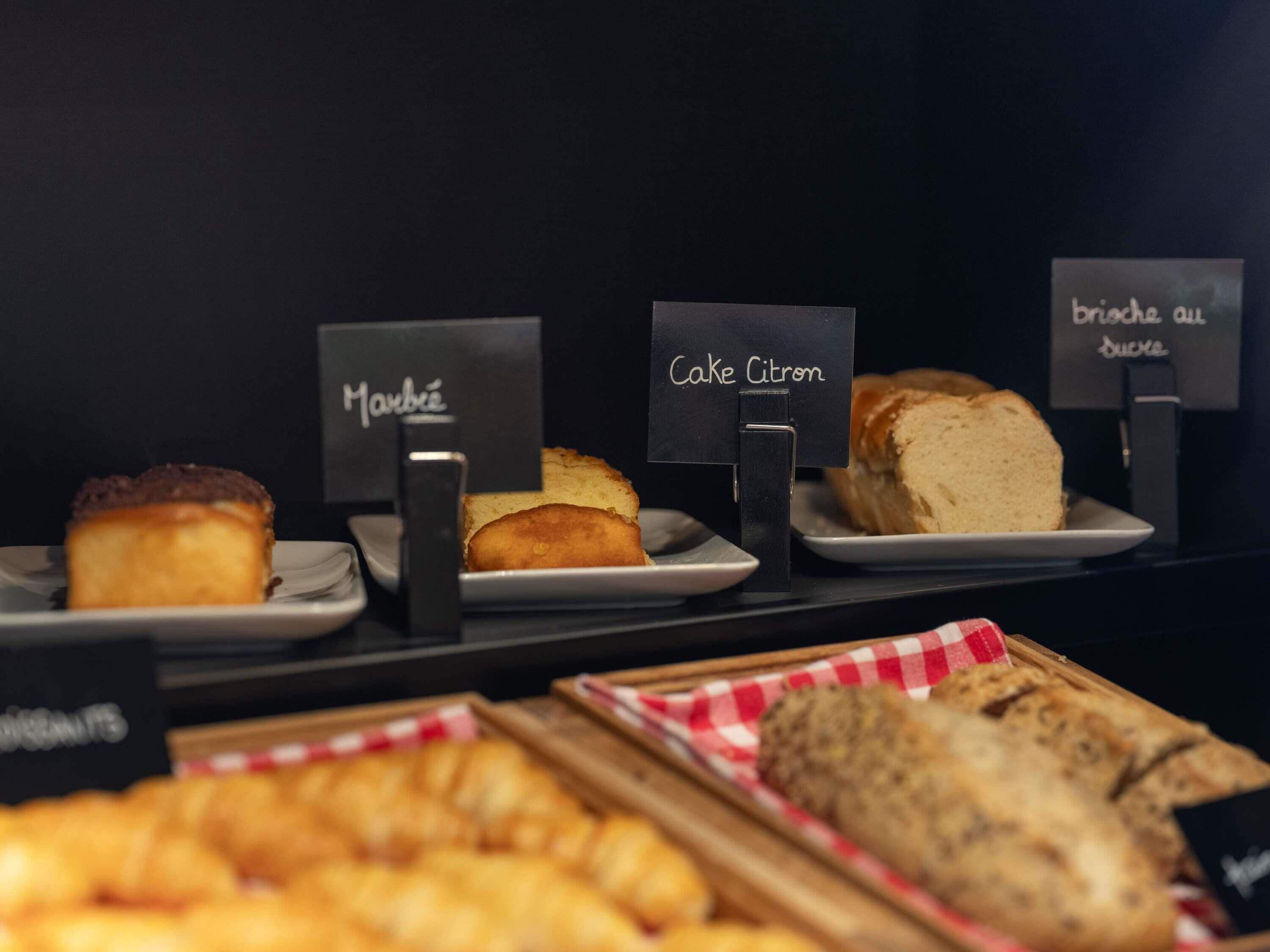 A display of various baked goods including cakes and bread, with labels indicating their names.