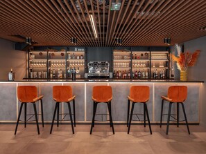 A bar area with a wooden ceiling, bar stools, and shelves stocked with glasses and bottles. - Novotel Paris Val de Fontenay (Fontenay-sous-Bois)