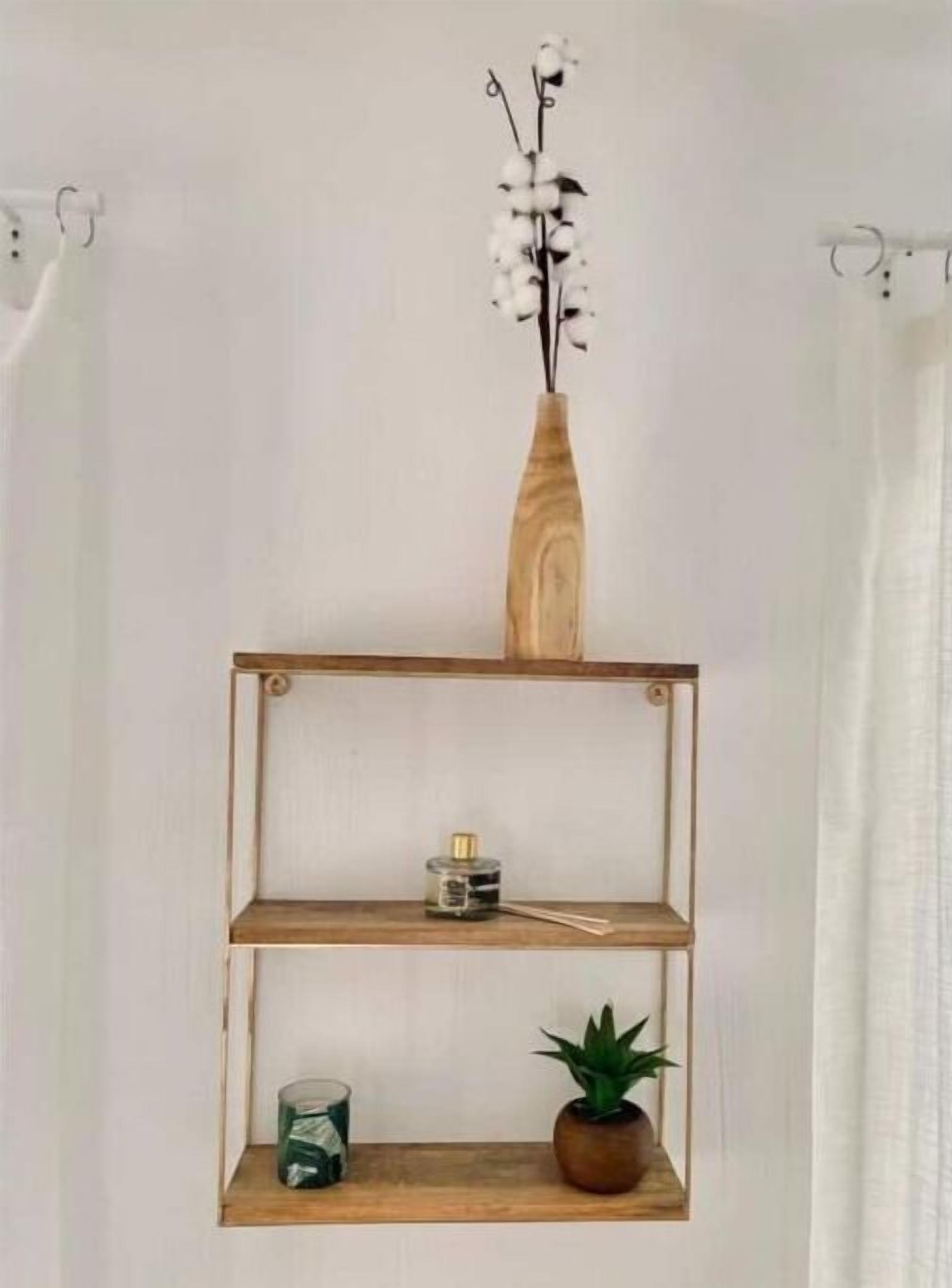 Une étagère en bois sur laquelle sont posés un vase de fleurs blanches, un petit flacon et une plante en pot.