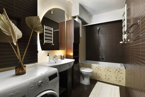 A modern bathroom with a white sink, a toilet, and a bathtub. - Elite Apartments Sunset (Gdansk)