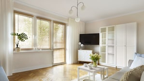 A modern living room with a sofa, a coffee table, a TV, and a cabinet. - Elite Apartments Sunset (Gdansk)