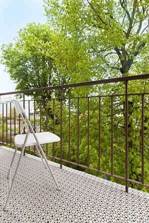 A balcony with a white metal chair and a metal railing. - Elite Apartments Sunset (Gdansk)