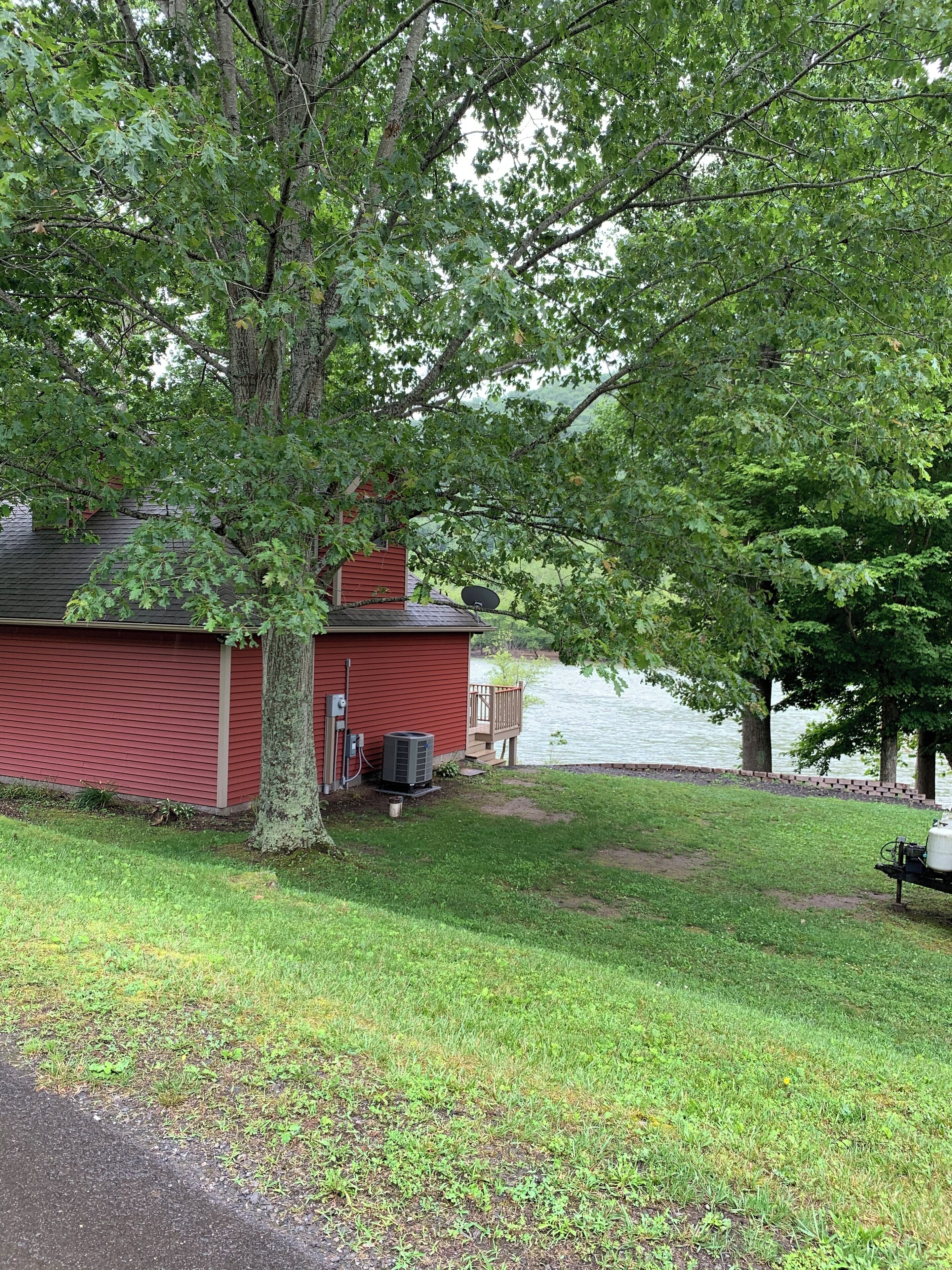A red building with a satellite dish, air conditioning unit, and a dock by a lake.