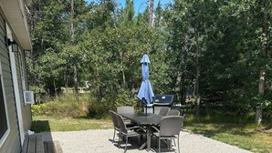 Eine Terrasse mit Tisch, Stühlen, einem Grill und einem blauen Sonnenschirm.
