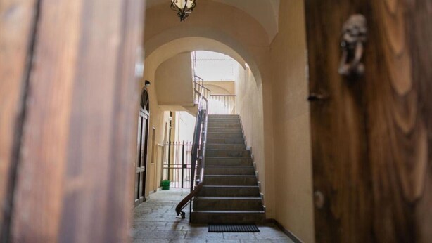 A staircase leading to an upper floor, flanked by arched doorways and a wooden door with a metal handle. - KALEA Guest House (Cefalù)