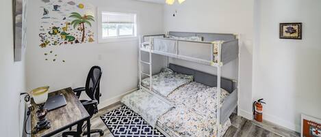 Habitación con literas, un escritorio, una silla y un ventilador de techo.