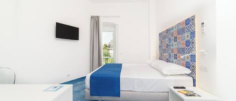 Une chambre à coucher moderne avec un lit, un téléviseur fixé au mur, une table de chevet et une vue sur l’extérieur.