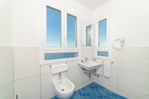 Une salle de bain moderne équipée d’un bidet, d’un lavabo et d’un miroir.