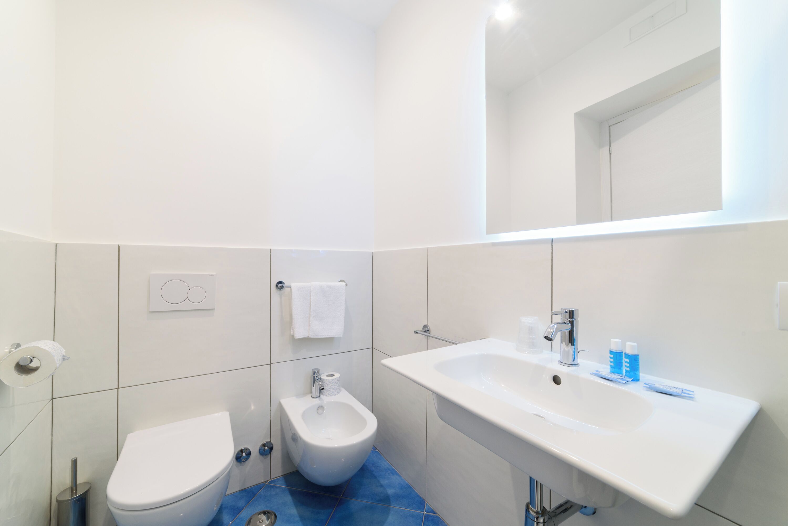 A modern bathroom with a toilet, bidet, and a large sink.