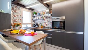 A modern kitchen with a wooden table, white chairs, and a stainless steel refrigerator. - I Mandorli - Lovely loft in Sardinia (Loceri)