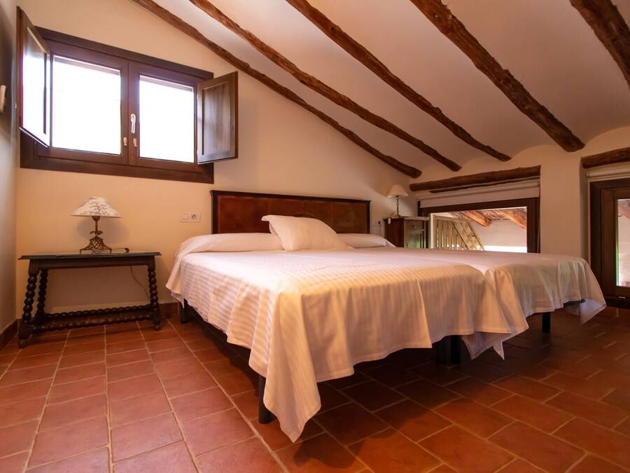 A bedroom with two beds, a nightstand, a lamp, and a window.