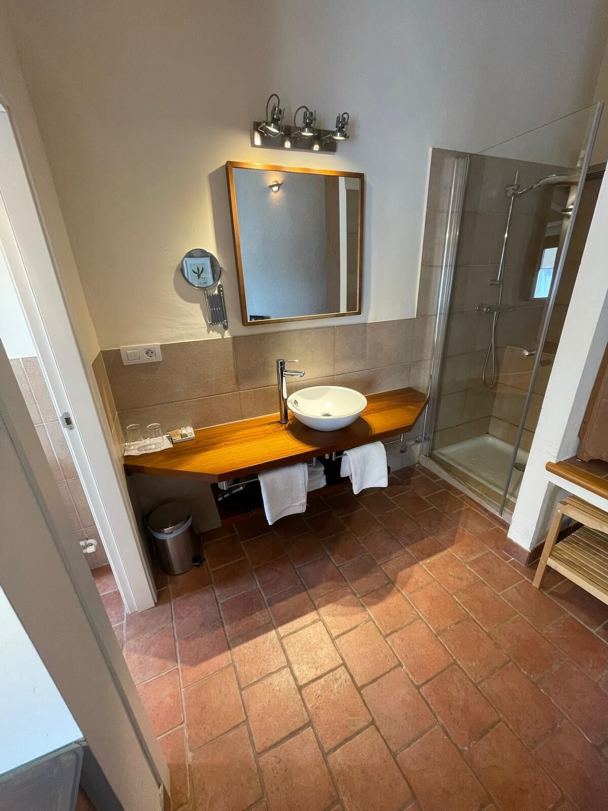 A bathroom with a wooden vanity, a white sink, a mirror, and a glass shower enclosure.