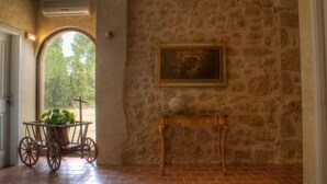 A stone-walled room with a rustic wooden table and a framed painting. - Torre alta de Ram (Alcaniz)